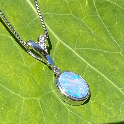 An oval cut black opal doublet necklace set in sterling silver with white zircon accent stones.