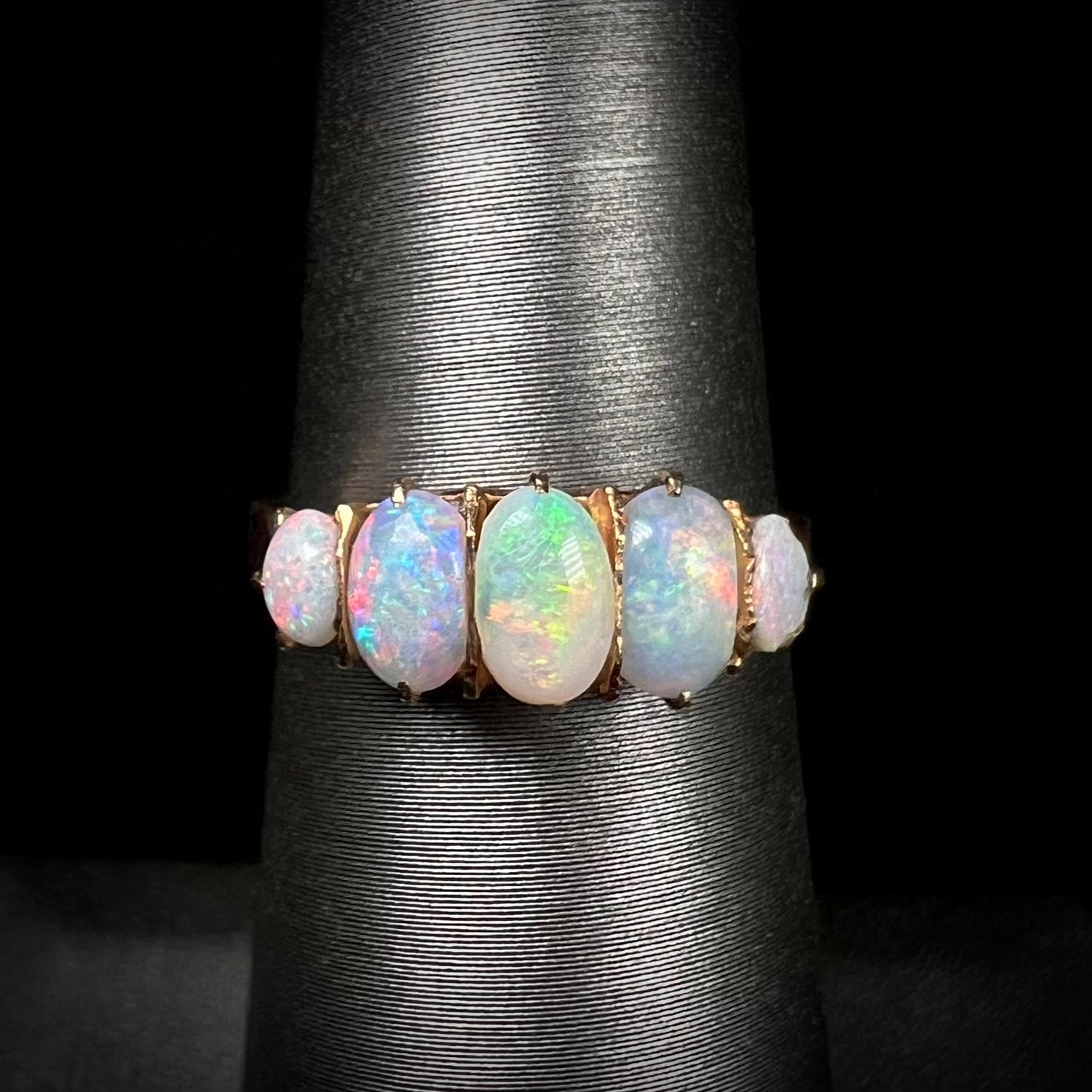 A ladies' Edwardian style 18 karat yellow gold ring set with five natural oval cut opal stones.