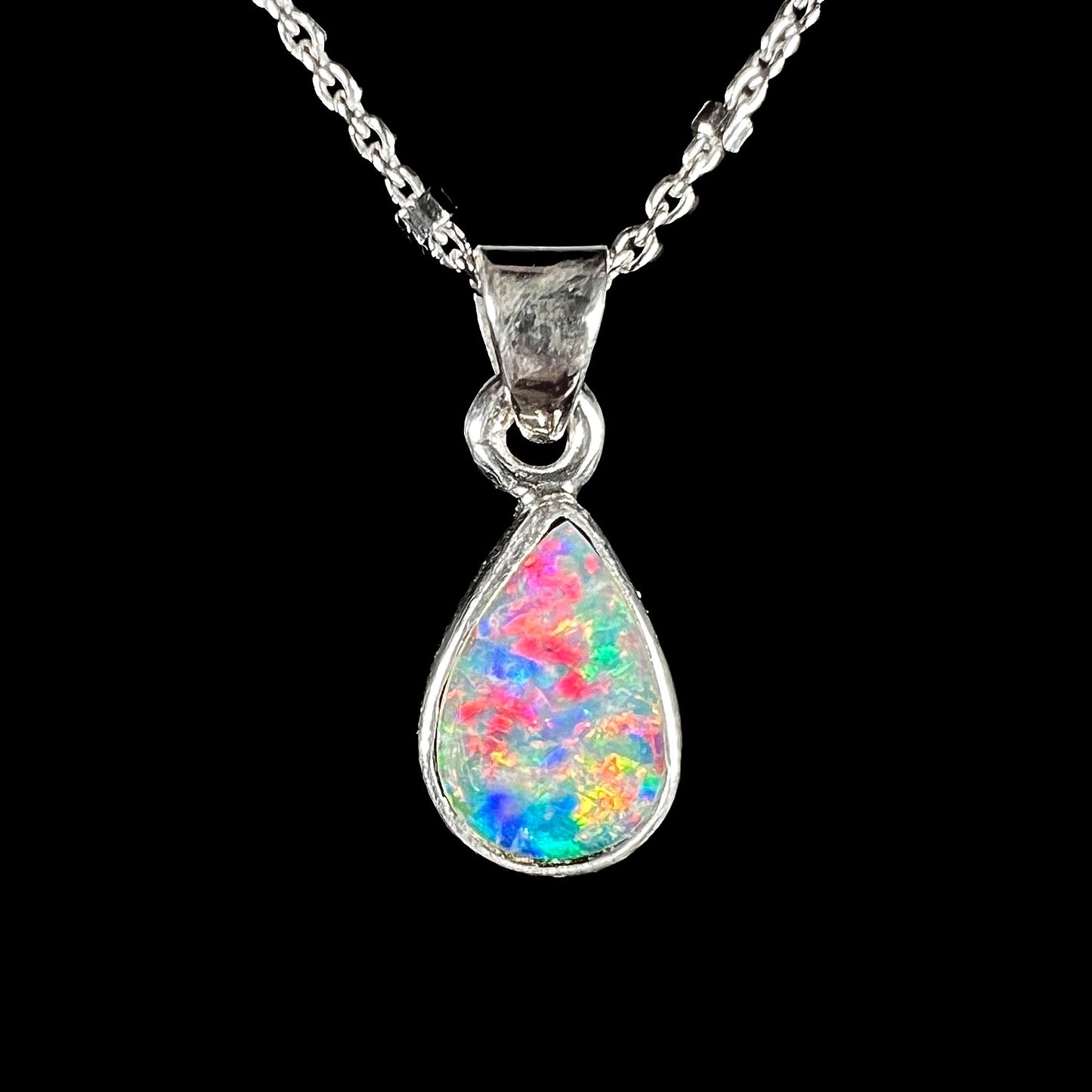 A pear shaped black opal necklace set in sterling silver.  The opal vividly flashes every color of the rainbow.