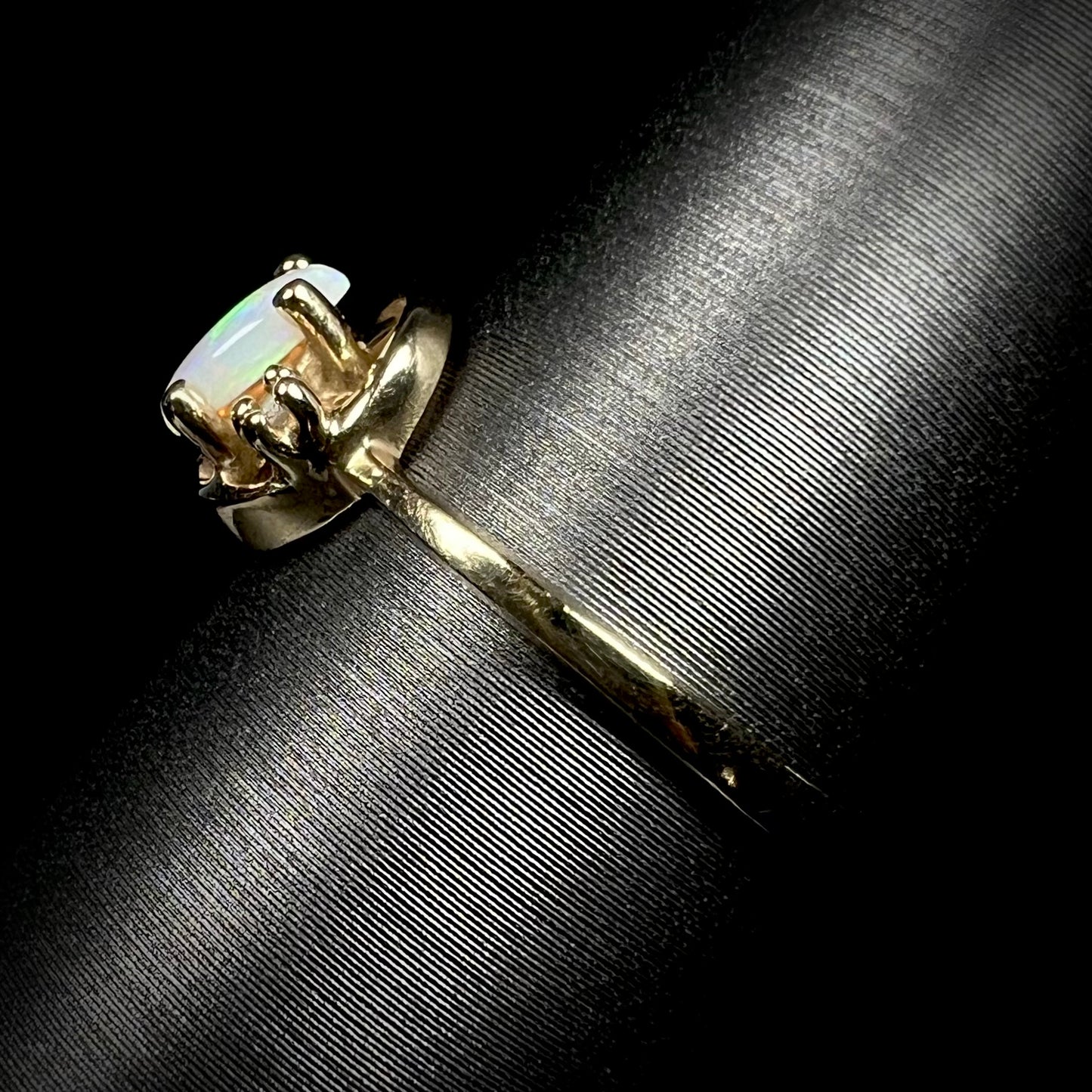 Side view of a dainty estate 10k yellow gold opal and diamond ring.  Light wear is visible on the ring's shank.