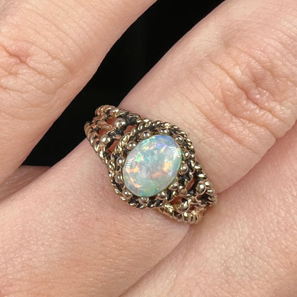 Close-up of an estate Australian opal solitaire ring in base metal, worn on a finger