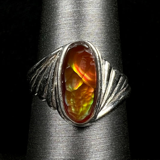 Close-up of estate Mexican fire agate ring in wavy sterling silver shank, shown on ring display.  Chips are seen along the fire agate, as is wear along the ring's shank.