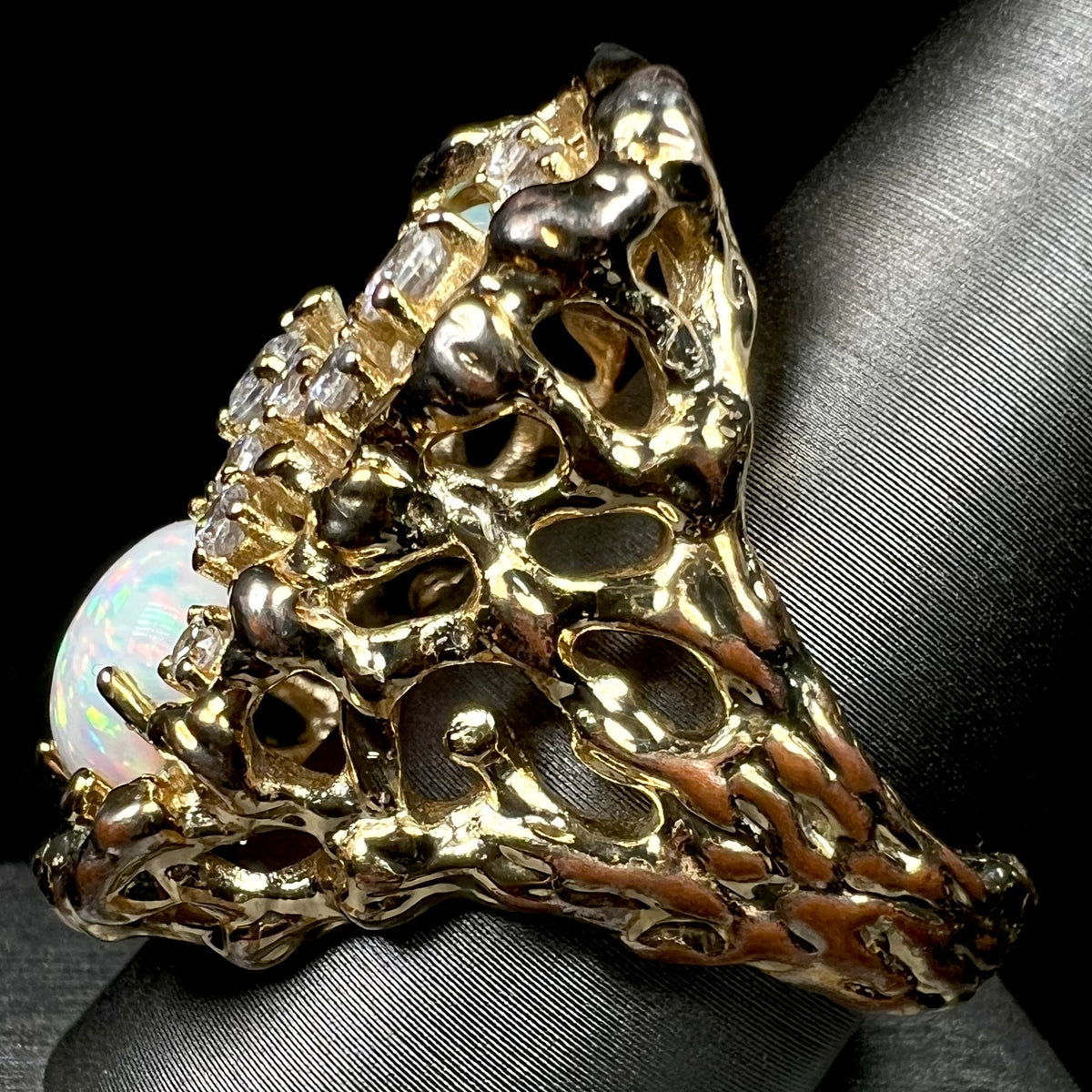 Side view of estate brutalist style men's ring set with lab-created opals and CZs; the gold plating is worn along the shank, showing copper tones.