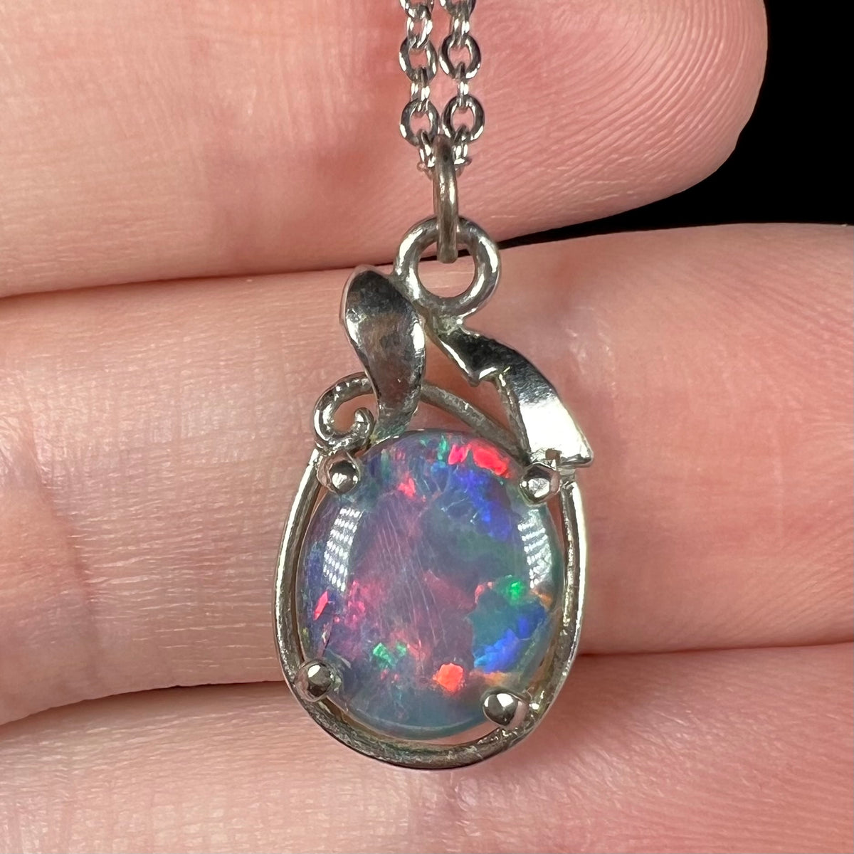Close-up of estate opal triplet pendant, held in hand