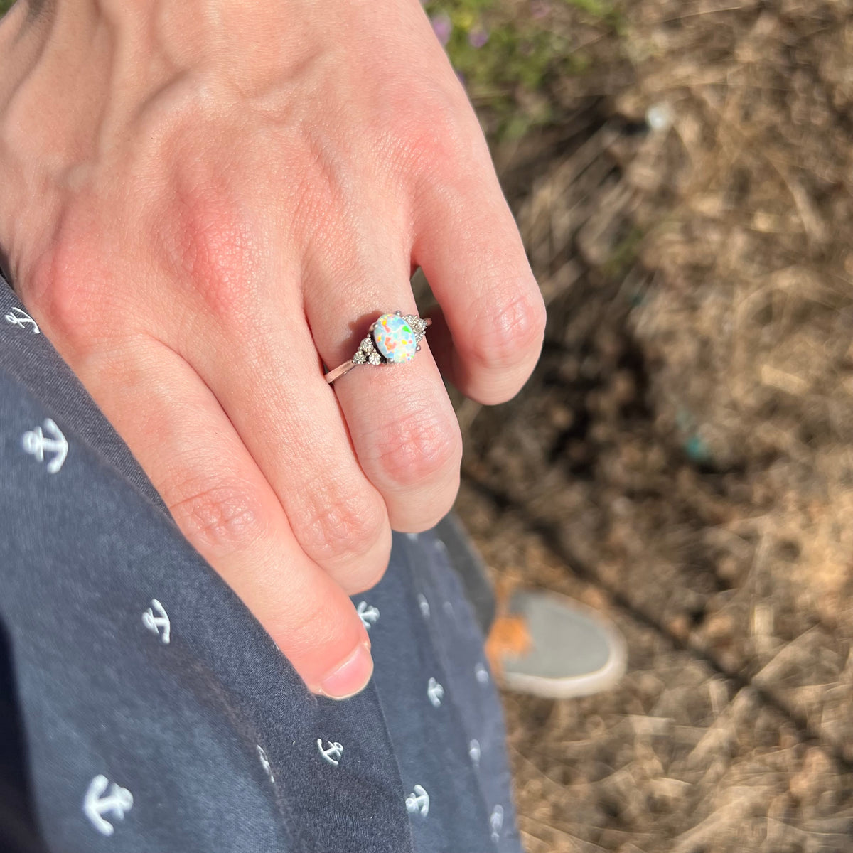 Close-up of person's hand resting on hip in sunlight wearing estate sterling silver opal and diamond women's ring.