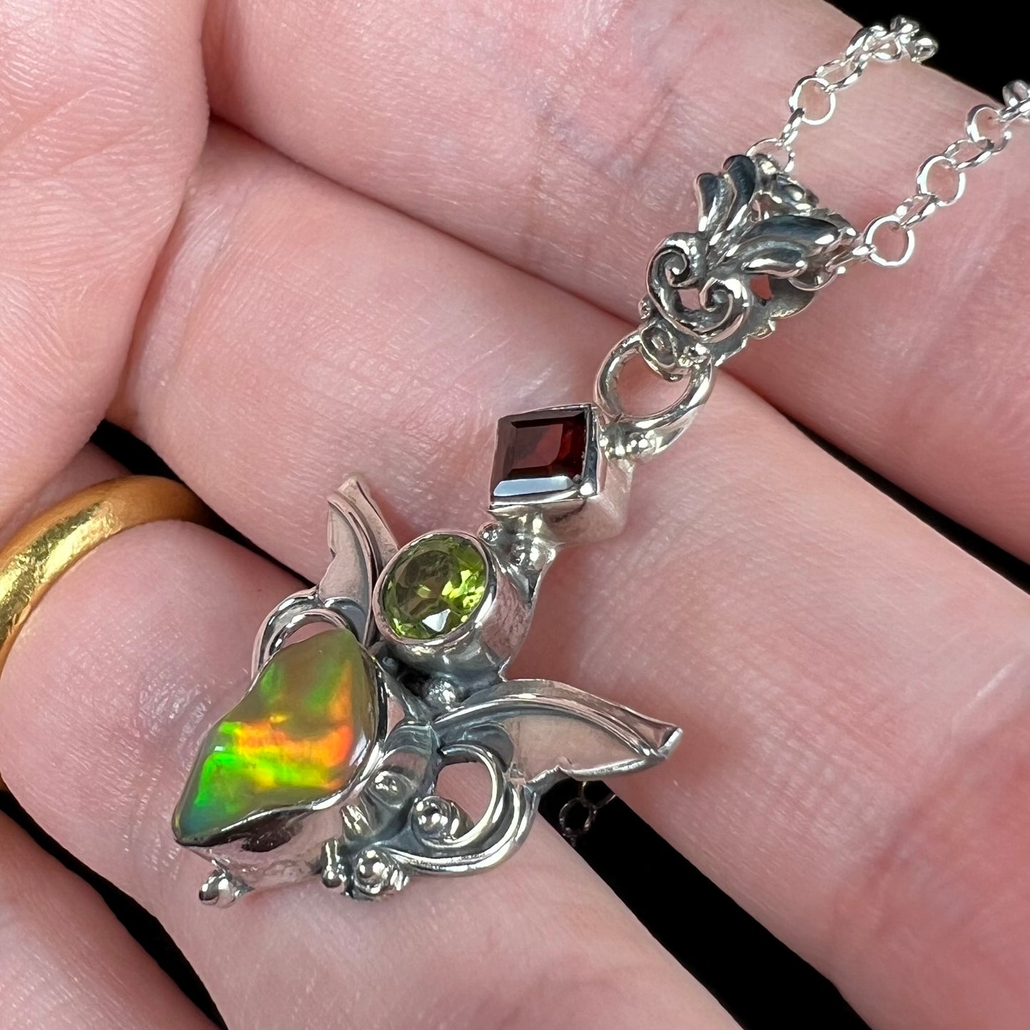 A sterling silver angel pendant set with an Ethiopian fire opal, peridot, and garnet.