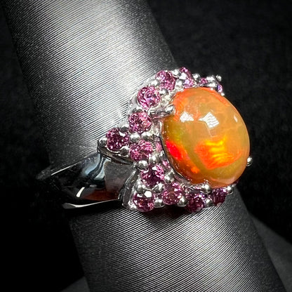Burnt orange colored Ethiopian fire opal and purple rhodolite garnet ring in silver on display, viewed from angle
