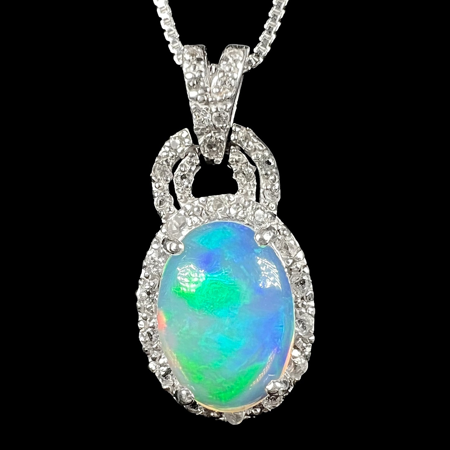 Close-up of women's sterling silver Ethiopian jelly opal pendant with white topaz halo on silver chain