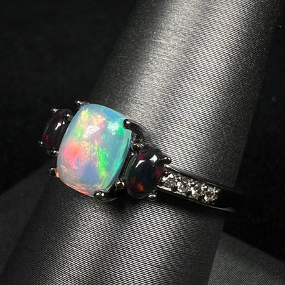Angled close-up of three-stone opal ring with black smoked Ethiopian opals and CZ accents, shown on ring display