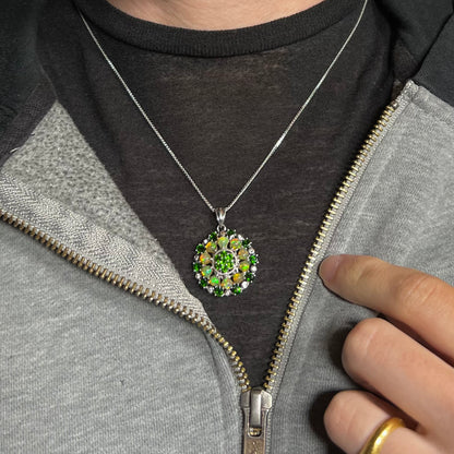 A silver Ethiopian opal and chrome diopside necklace worn against a dark shirt under an unzipped hoodie.
