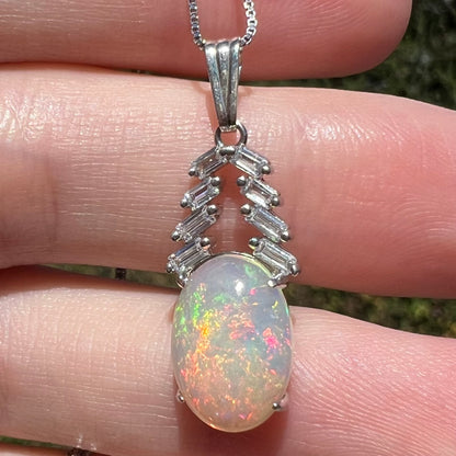 Close-up of women's silver Ethiopian opal and CZ drop pendant held in natural light