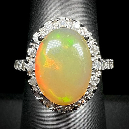 A sterling silver Ethiopian fire opal ring with a CZ halo shown from the front against a black backdrop.