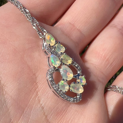 Angled close-up view of an Ethiopian opal and CZ necklace, held in a hand and shown in sunlight.