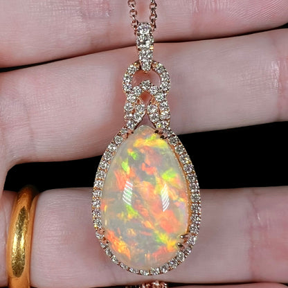 Close-up front view of an Ethiopian opal and diamond halo necklace by Le Vian shown held in a hand under LED studio lightning.