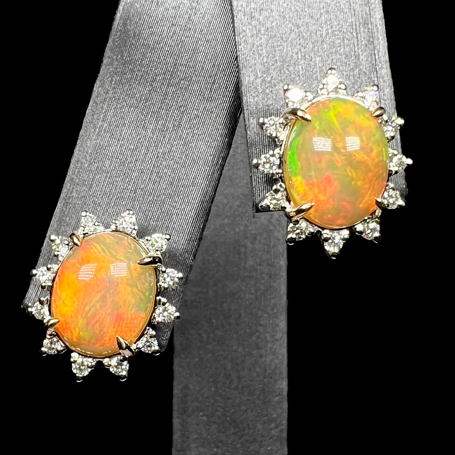 Pair of 14k gold Ethiopian opal and diamond halo stud earrings on earring display