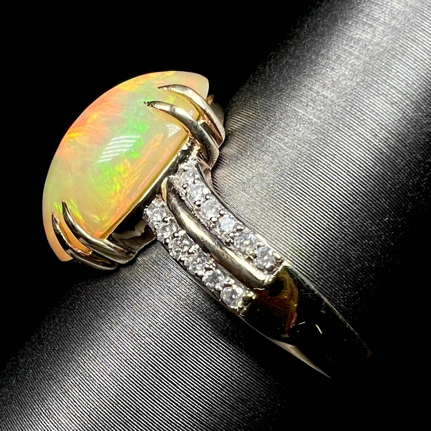 Side view of Ethiopian opal and diamond pave ring in 14k gold on display, showing ring's shank