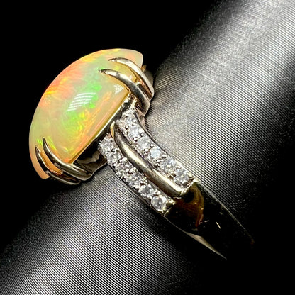 Side view of Ethiopian opal and diamond pave ring in 14k gold on display, showing ring's shank