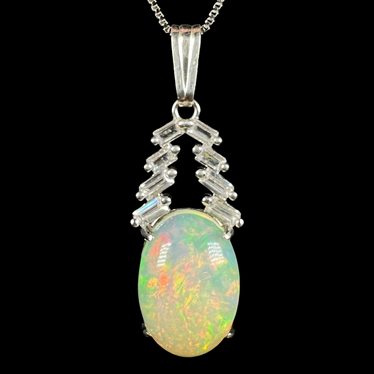 Close-up of women's sterling silver Ethiopian opal and emerald cut CZ drop pendant on chain