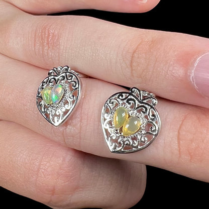 A pair of dangling sterling silver filigree heart earrings, each set with two Ethiopian opals.