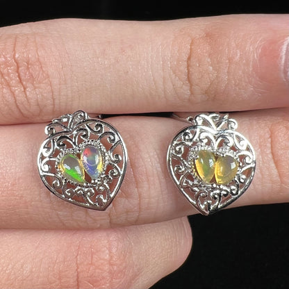 A pair of dangling sterling silver filigree heart earrings, each set with two Ethiopian opals.