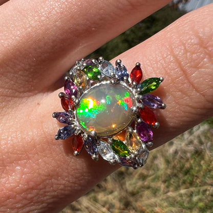 Front close-up of an Ethiopian opal fruit salad ring, worn on a finger and shown in natural sunlight.
