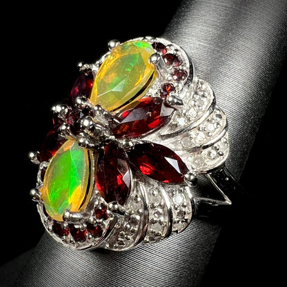 An Ethiopian opal, garnet, and diamond ring in silver, shown from an angle.