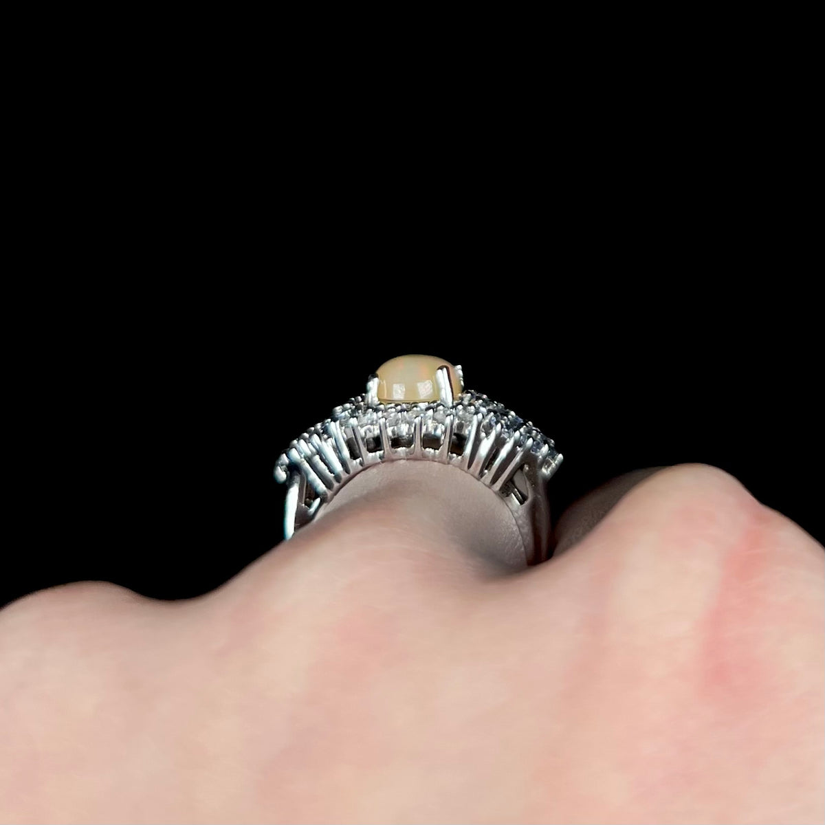 Sterling silver Ethiopian opal and gemstone cluster ring shown from side gallery profile view, worn on hand