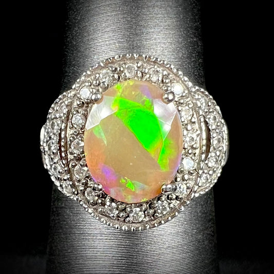 Front view of silver Ethiopian opal ring with CZ halo.  The faceted opal shows a diagonal bright green flash.