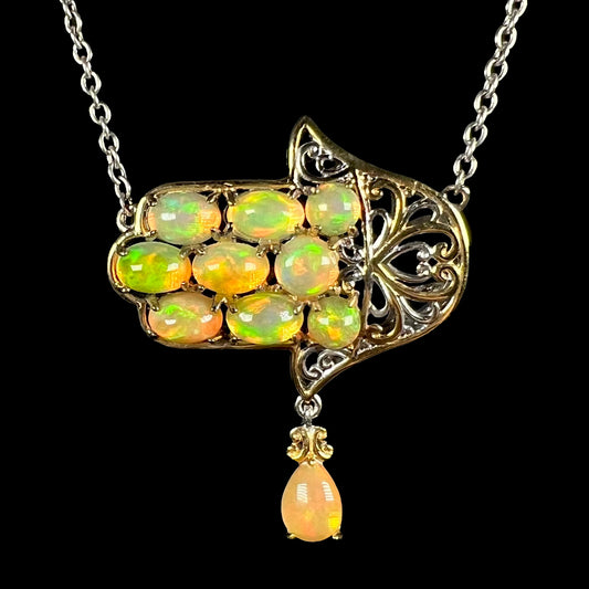 A two-tone silver Ethiopian opal hamsa necklace with a filigree design, shown from the front against black background.
