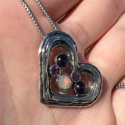 A sterling silver heart necklace set with a round Ethiopoian opal, two amethysts, and two rhodolite garnets.