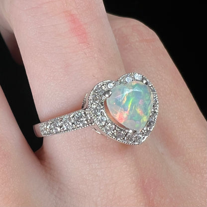 Silver Ethiopian opal heart design ring with CZ pave and halo design, worn on finger