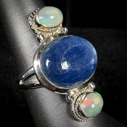 An Ethiopian opal-accented kyanite ring in sterling silver, shown at an angle against dark backdrop.