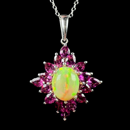 A sterling silver Ethiopian opal and rhodolite garnet spray necklace, shown close-up against a black background.