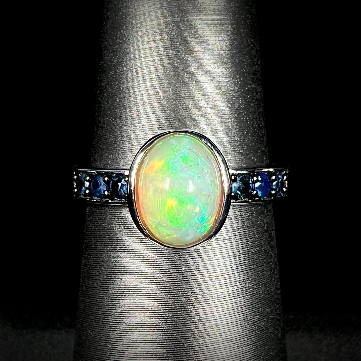 Front view of silver Ethiopian opal and topaz-accented ring against black background.