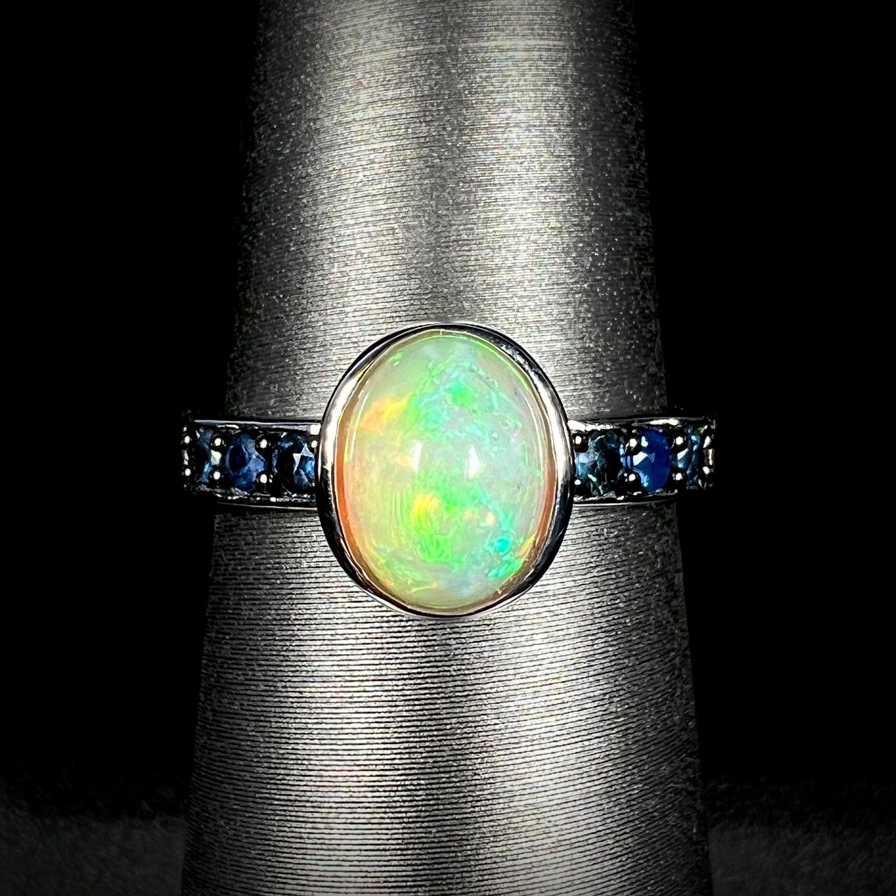 Front view of silver Ethiopian opal and topaz-accented ring against black background.
