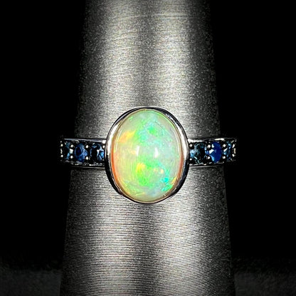 Front view of silver Ethiopian opal and topaz-accented ring against black background.