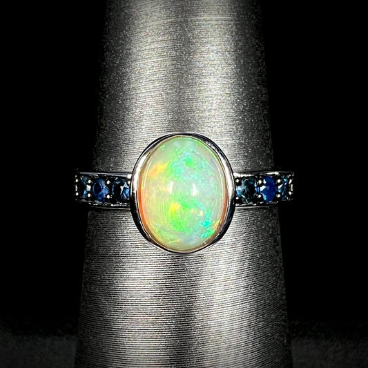 Front view of silver Ethiopian opal and topaz-accented ring against black background.