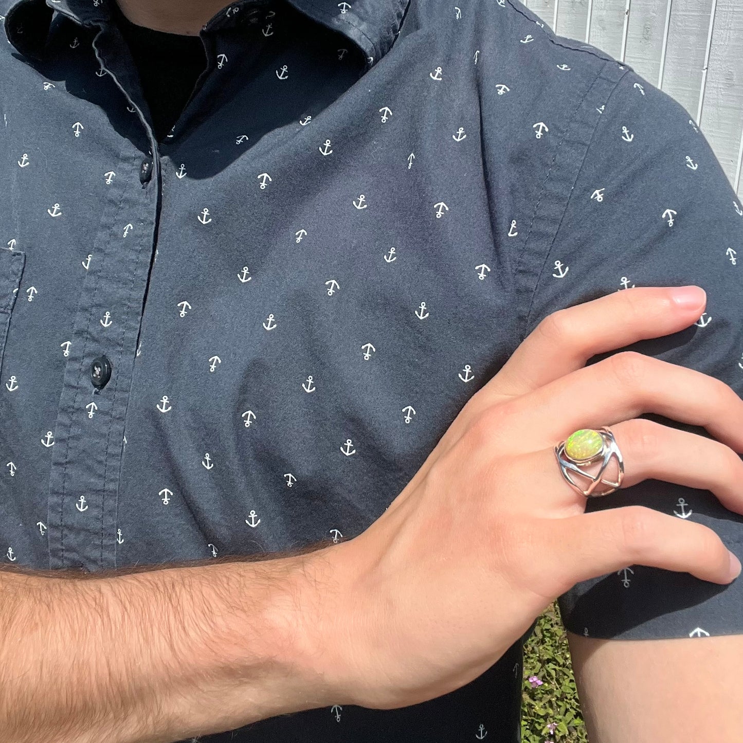 An Ethiopian opal solitaire ring worn on a hand, resting on a model's shoulder.