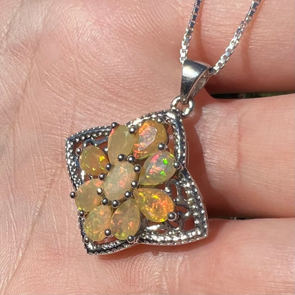 An Ethiopian opal star necklace shown in the sunlight in a hand at an angle.  The opals have orange color play.