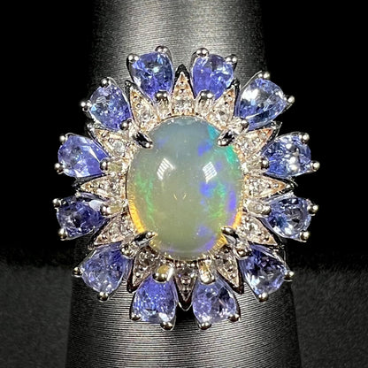An Ethiopian opal starburst ring with a tanzanite halo, shown from the front against a black background.