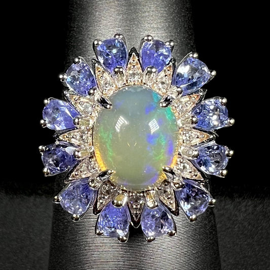 An Ethiopian opal starburst ring with a tanzanite halo, shown from the front against a black background.