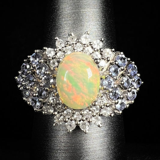 Close-up of women's sterling silver Ethiopian opal ring with clustered spray of tanzanite and white topaz accents, on ring display