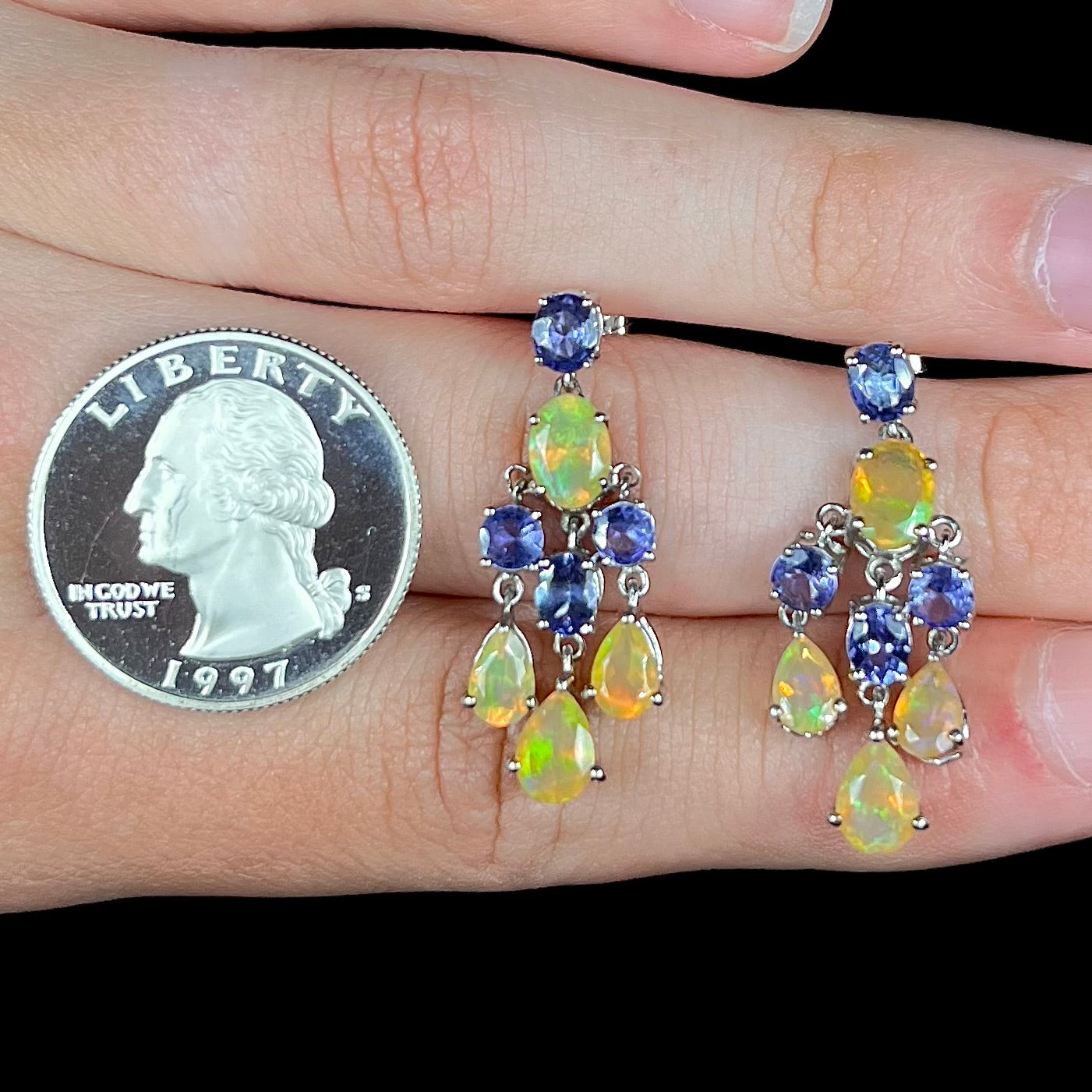 A pair of dangling sterling silver Ethiopian opal and tanzanite chandelier earrings, shown next to a quarter coin.