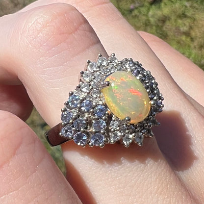 Macro view of Ethiopian opal and tanzanite ring, worn on finger in sunlight
