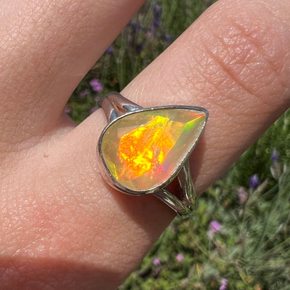 A unisex sterling silver ring set with a faceted pear shaped Ethiopian fire opal.  The opal plays orange, red, and green colors.