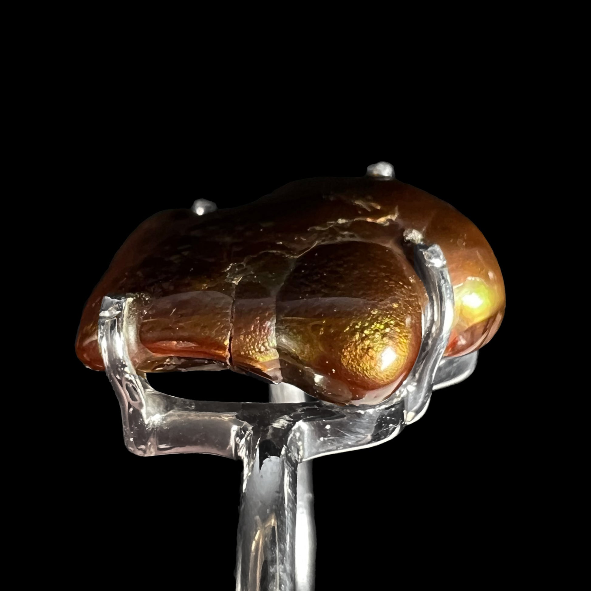 Side macro view of cracked fire agate stone highlighting internal fracture.