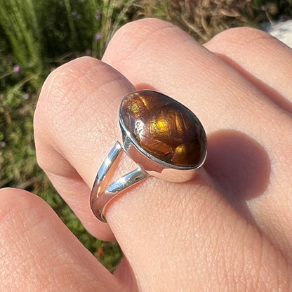 Angled close-up view of a sterling silver Mexican fire agate ring with a split shank worn on finger.