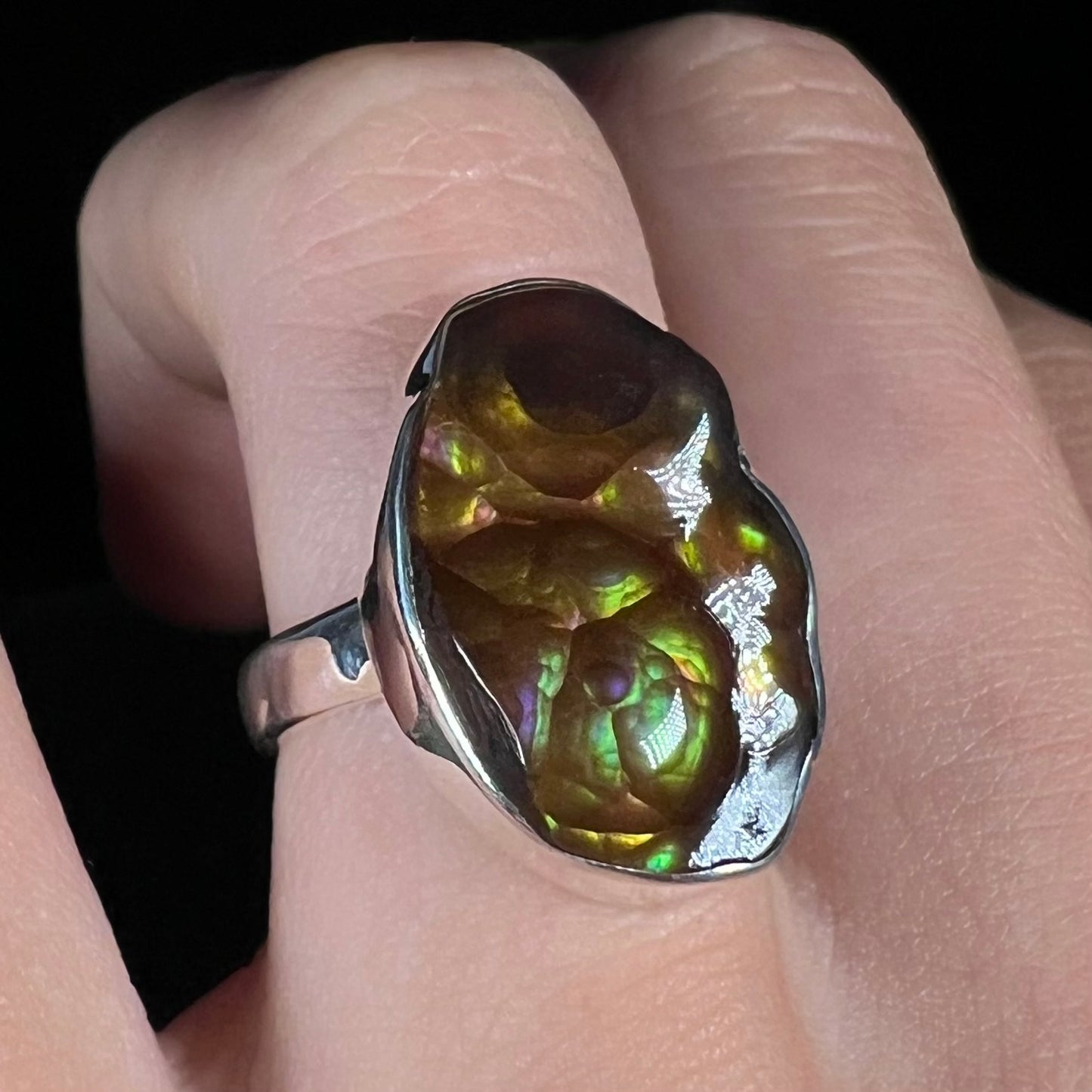 Angled close-up of a sterling silver Mexican fire agate ring with green and purple iridescence.
