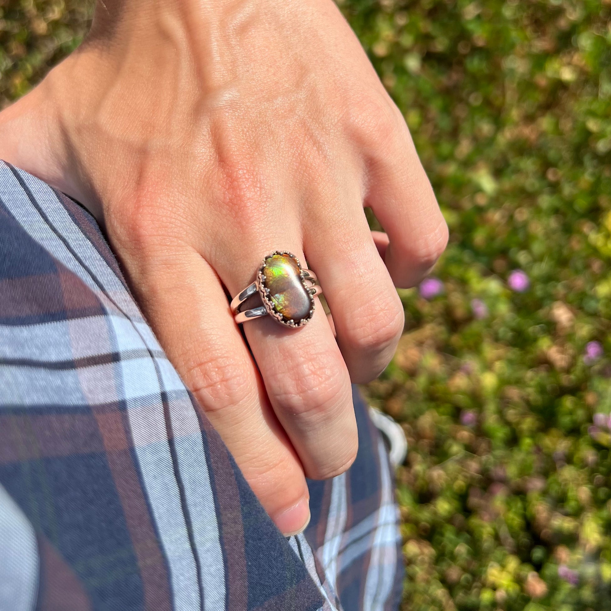 Green fire agate ring worn on a hand in the sunlight, resting on the model's hip.