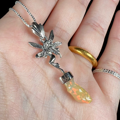 A sterling silver fairy necklace with an Ethiopian fire opal crystal, shown close-up at an angle in a hand.